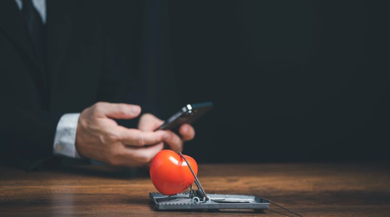 Online internet romance scam or swindler in website application dating concept, Love is bait or victim, Red heart in a rat trap, Young business people using mobile phone searching love dating girl friend on internet.